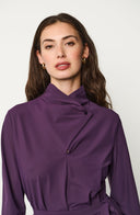 Woman wearing a purple blouse against a white background
